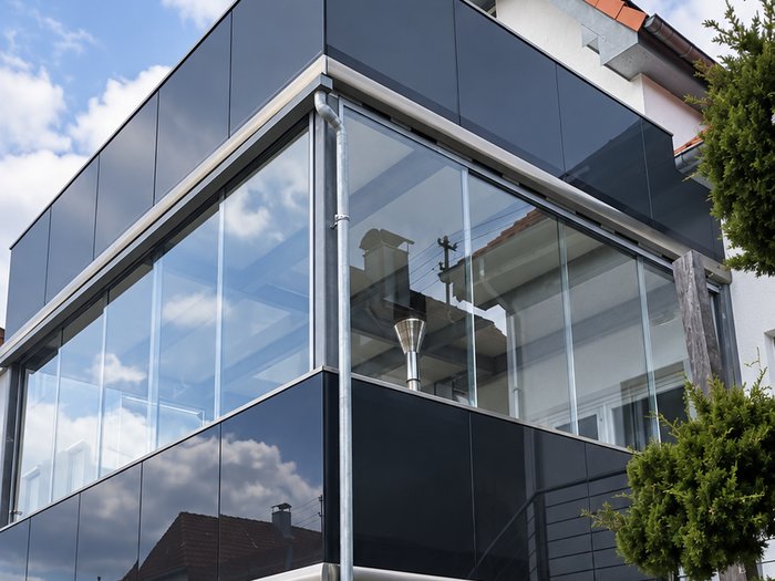 Verglaster Balkonanbau mit dunkler Aluminiumverkleidung an einem Einfamilienhaus.