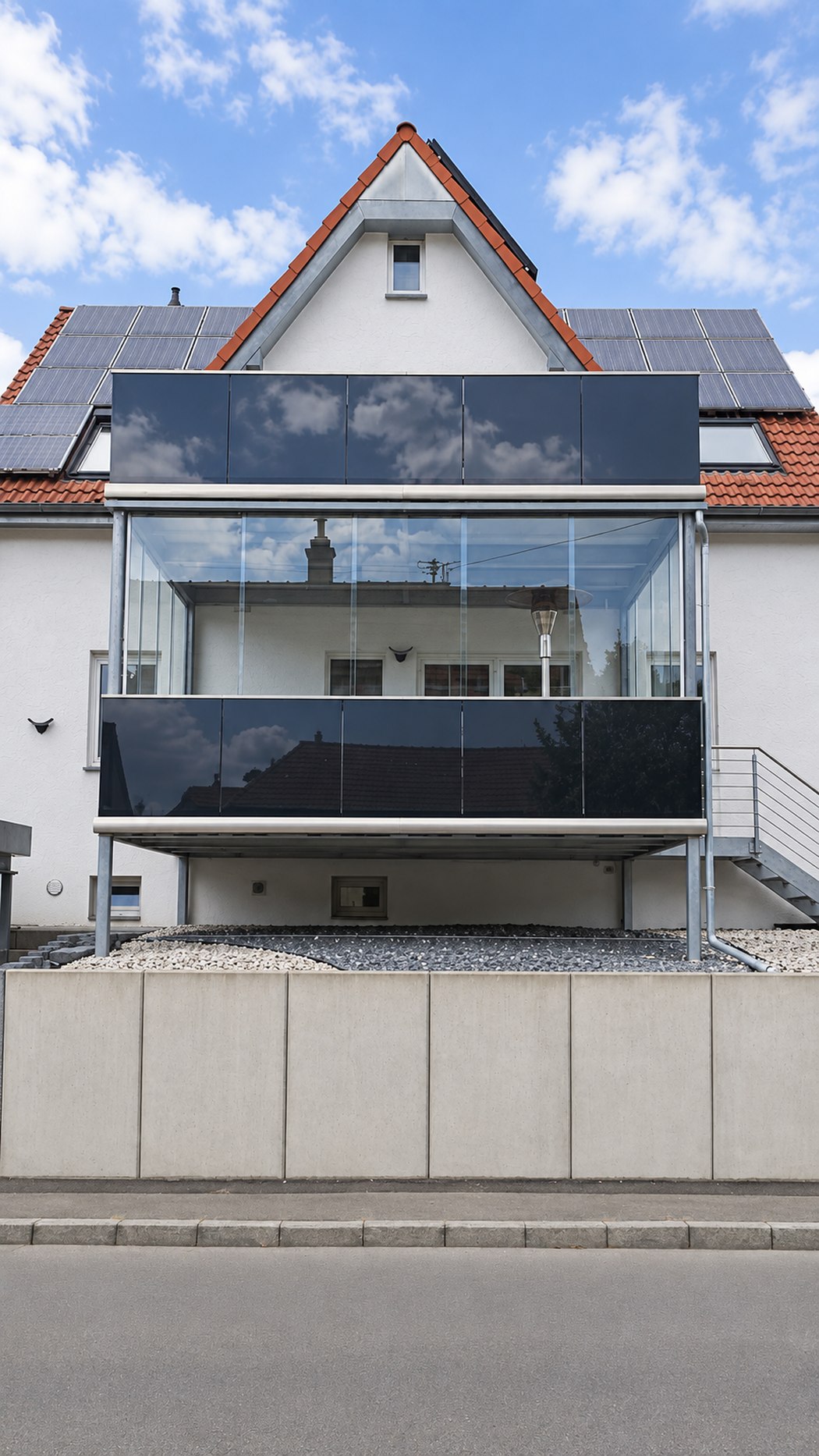 Verglaster Balkonanbau mit dunkler Aluminiumverkleidung, Frontalansicht am Wohnhaus.