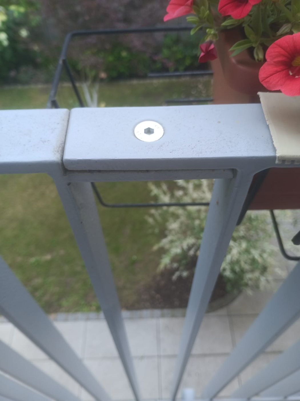 Detail eines Metallgeländers mit senkrechten Stäben und verschraubtem Handlauf.