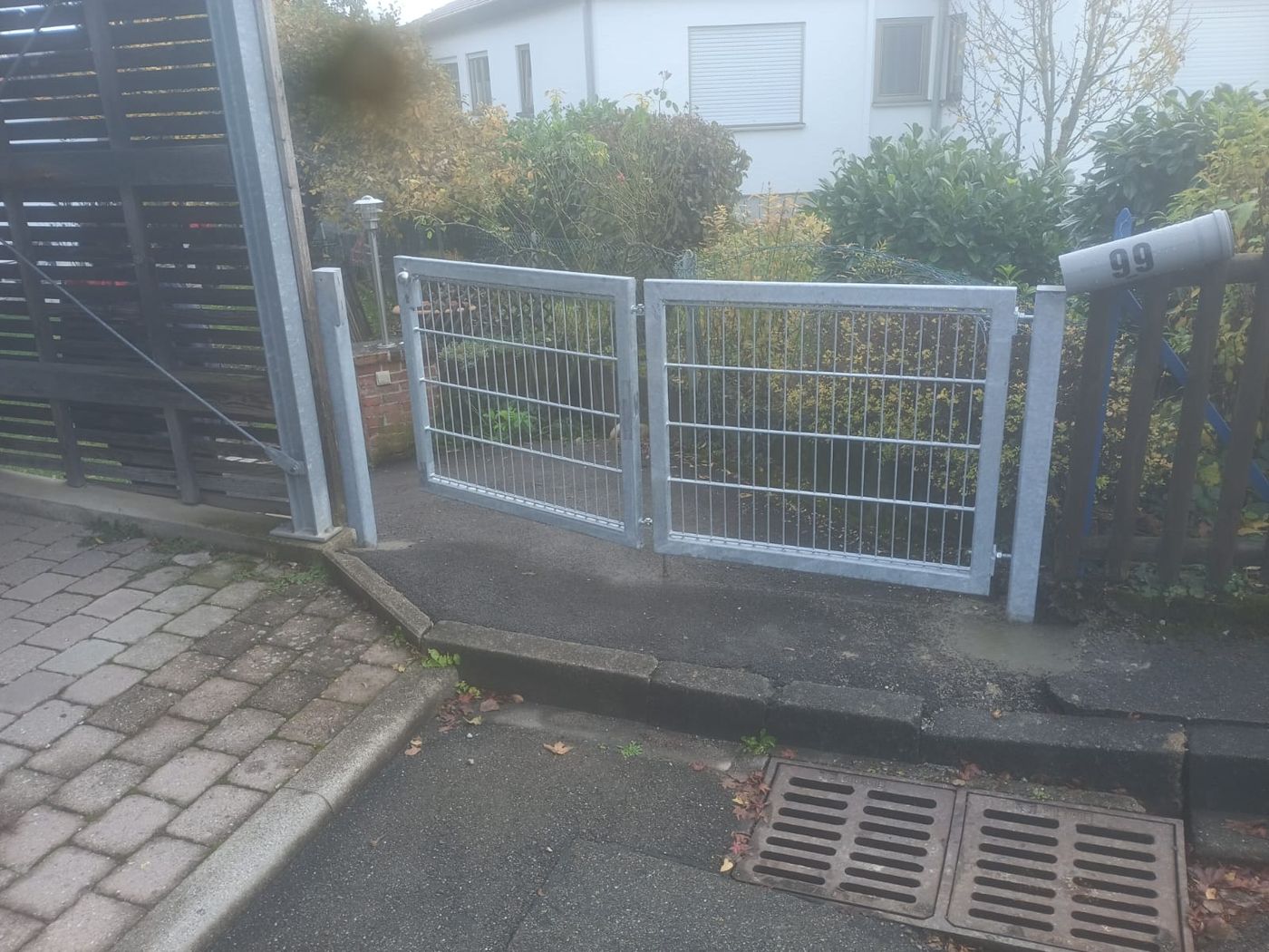 Helles zweiflügeliges Gartentor mit Gitterfüllung neben einer Außentreppe.